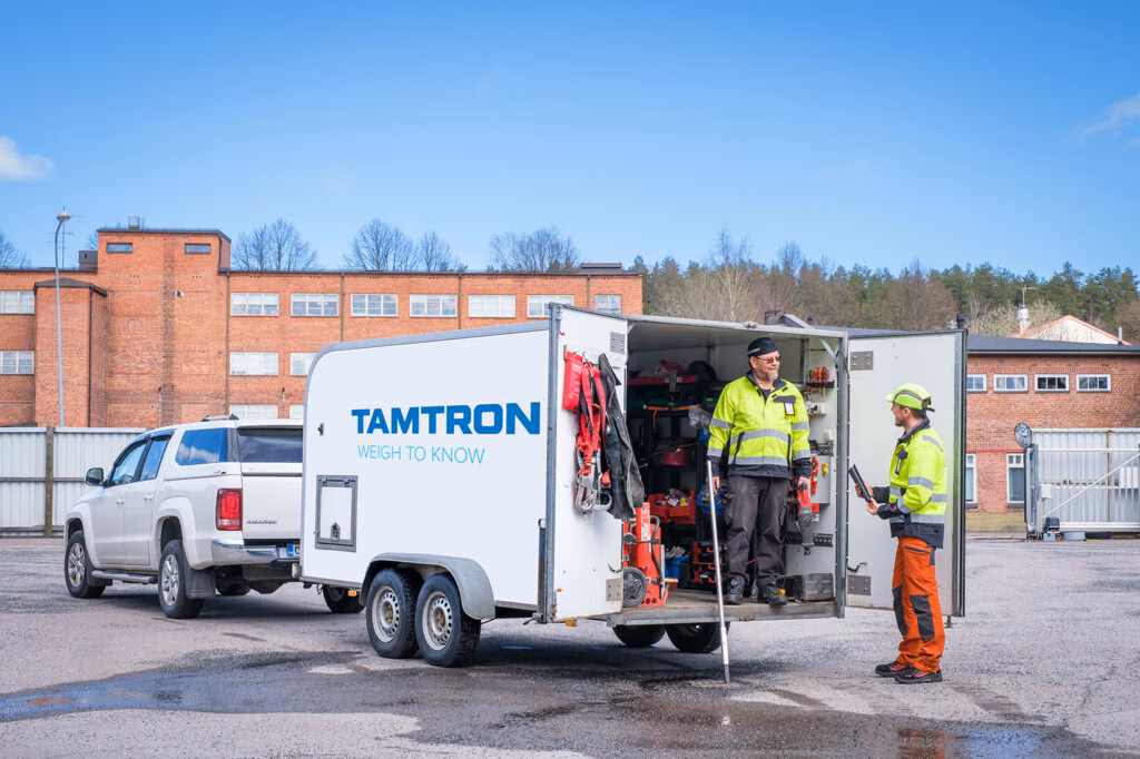 Kaksi miestä Tamtronin huoltovaunun vieressä, jossa työkaluja ja huoltovarusteita