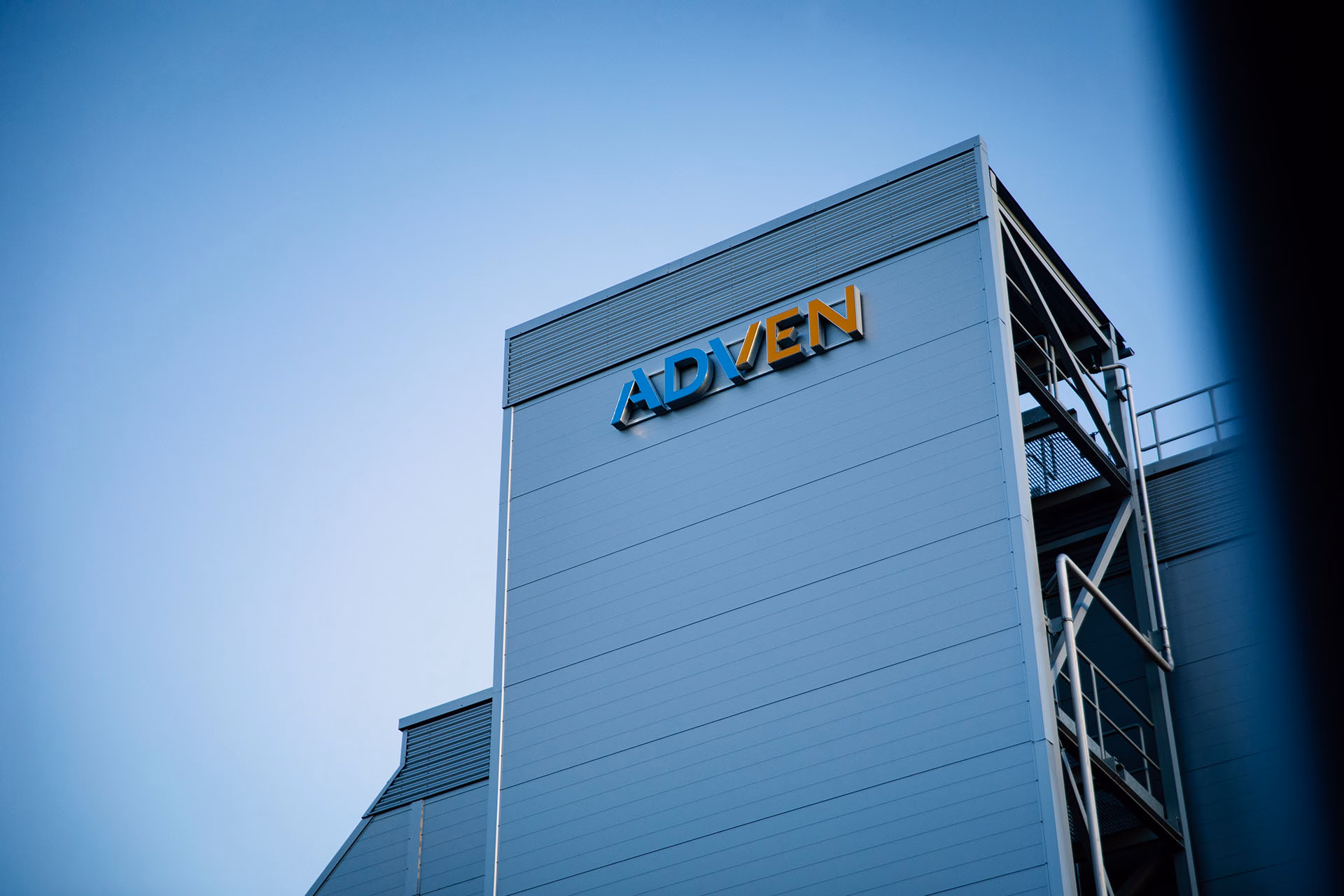 Part of a company building with the Adven logo, with a blue sky in the background
