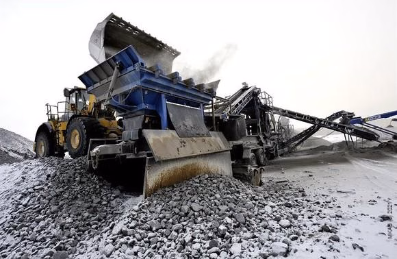An industrial site with a wheel loader, a conveyor belt and piles of rocks