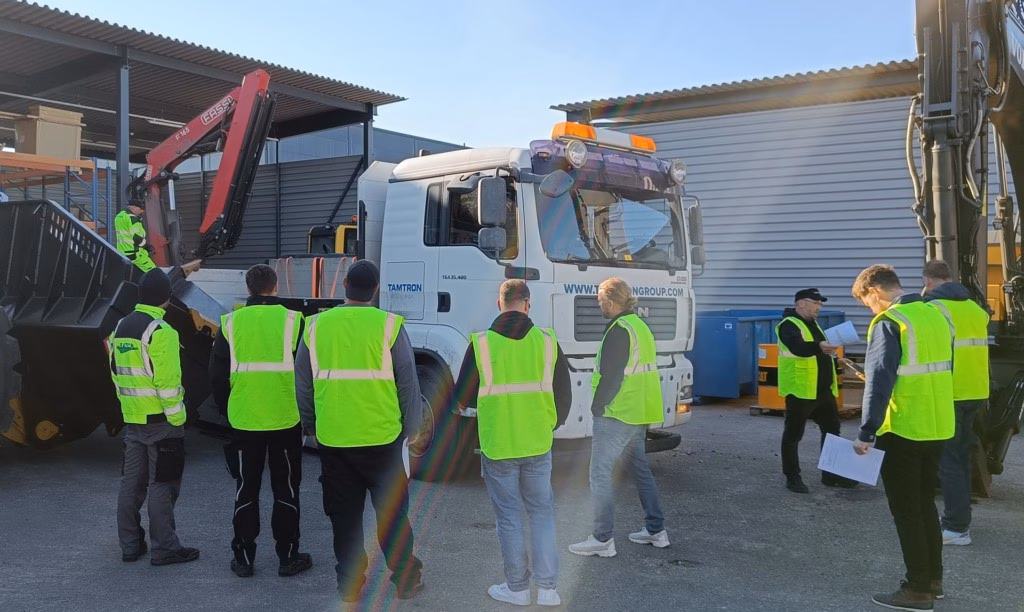 Arbeiter neben einem Lkw mit Kran in einem Außenarbeitsbereich