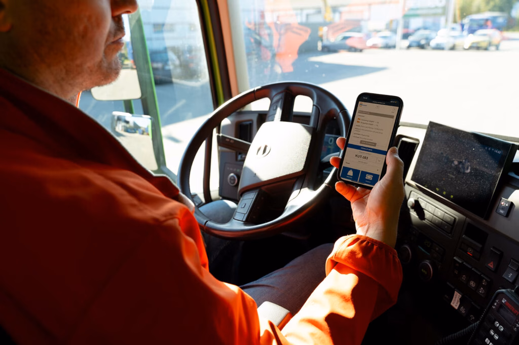 Řidič nákladního vozu uvnitř vozidla drží telefon, na kterém je zobrazeno rozhraní mScales