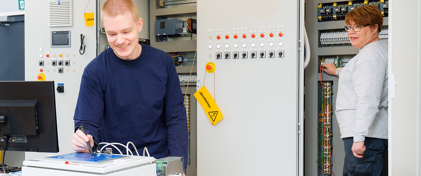 Dve osoby pracujú vedľa elektrického rozvádzača