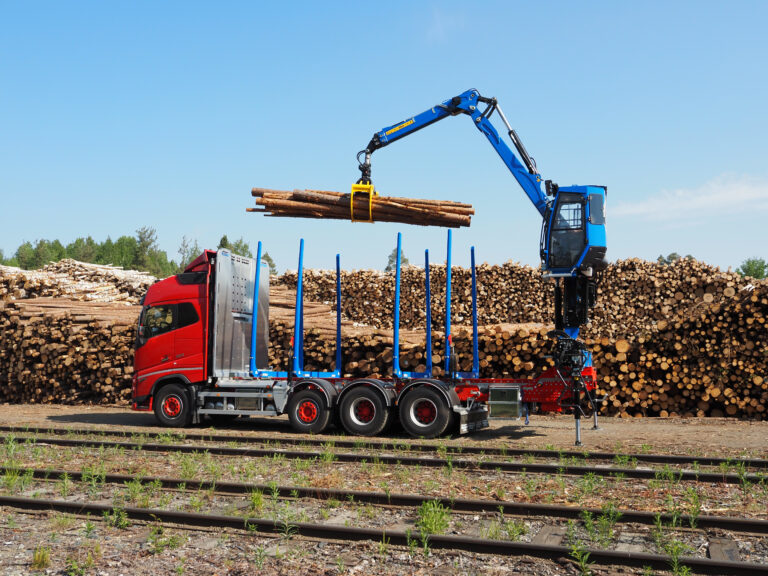 Timber truck with crane loading logs at a wood yard