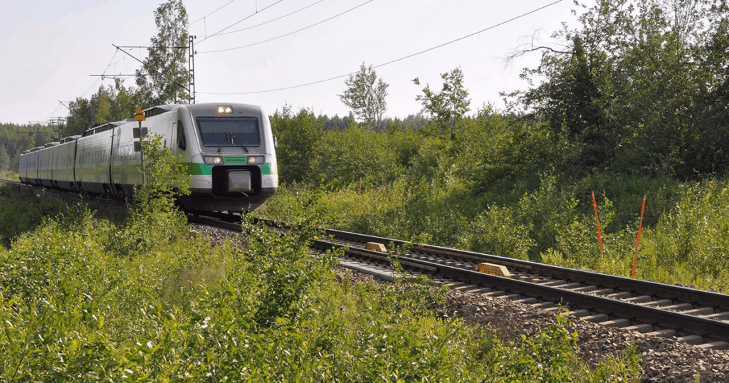 Train moving on railway tracks, with green vegetation around