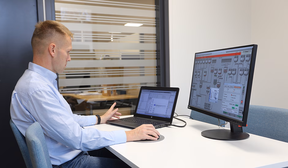 Engineer working on automation system design using laptop and external monitor in an office environment