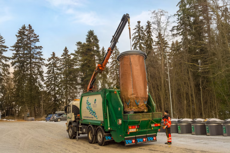 Waste collection truck emptying a recycling container with a crane