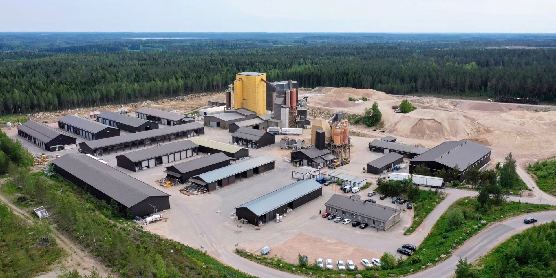 Aerial view of Fescon production facility with industrial buildings, storage areas and surrounding forest landscape