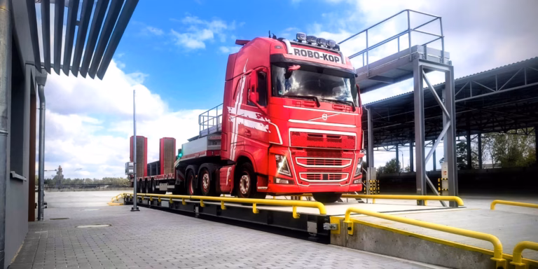 Red truck positioned on a truck scale at an industrial weighing station
