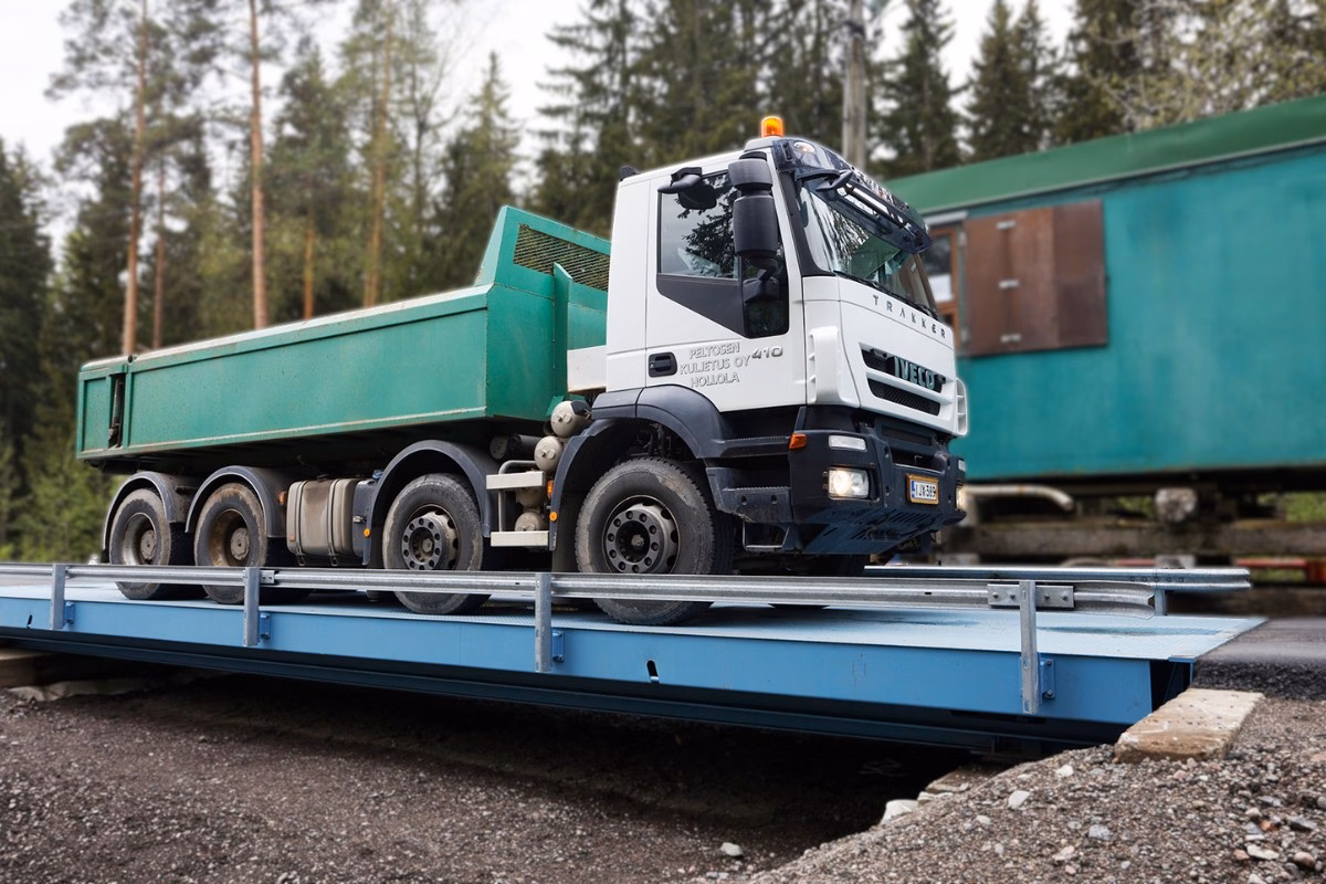 Kuorma-auto siirrettävällä teräksisellä autovaa’alla, taustalla metsää