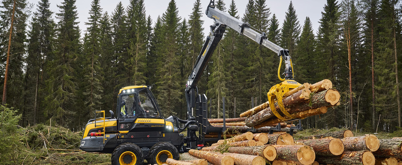 Ponsse forwarder loading logs with its crane in a spruce forest