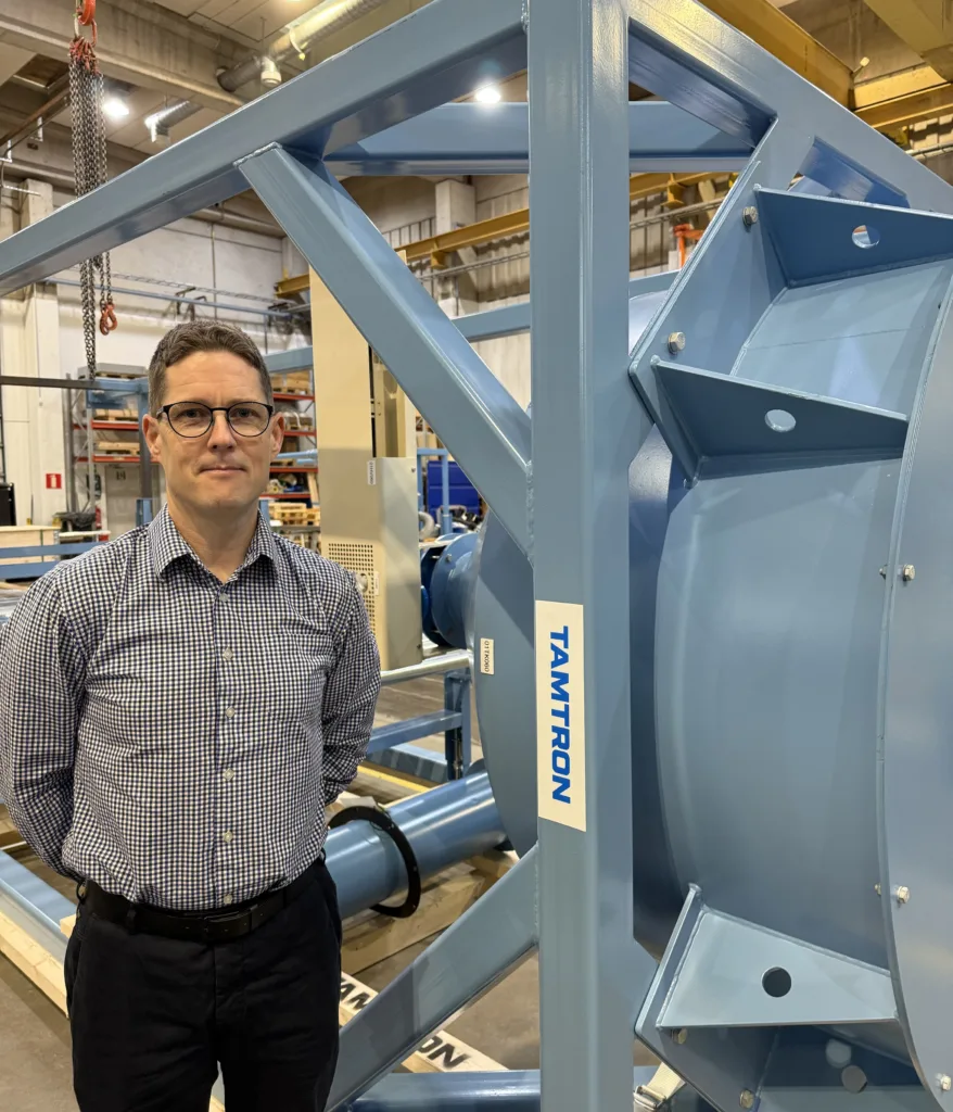 Tamtron expert in an assembly hall with industrial weighing equipment in the background